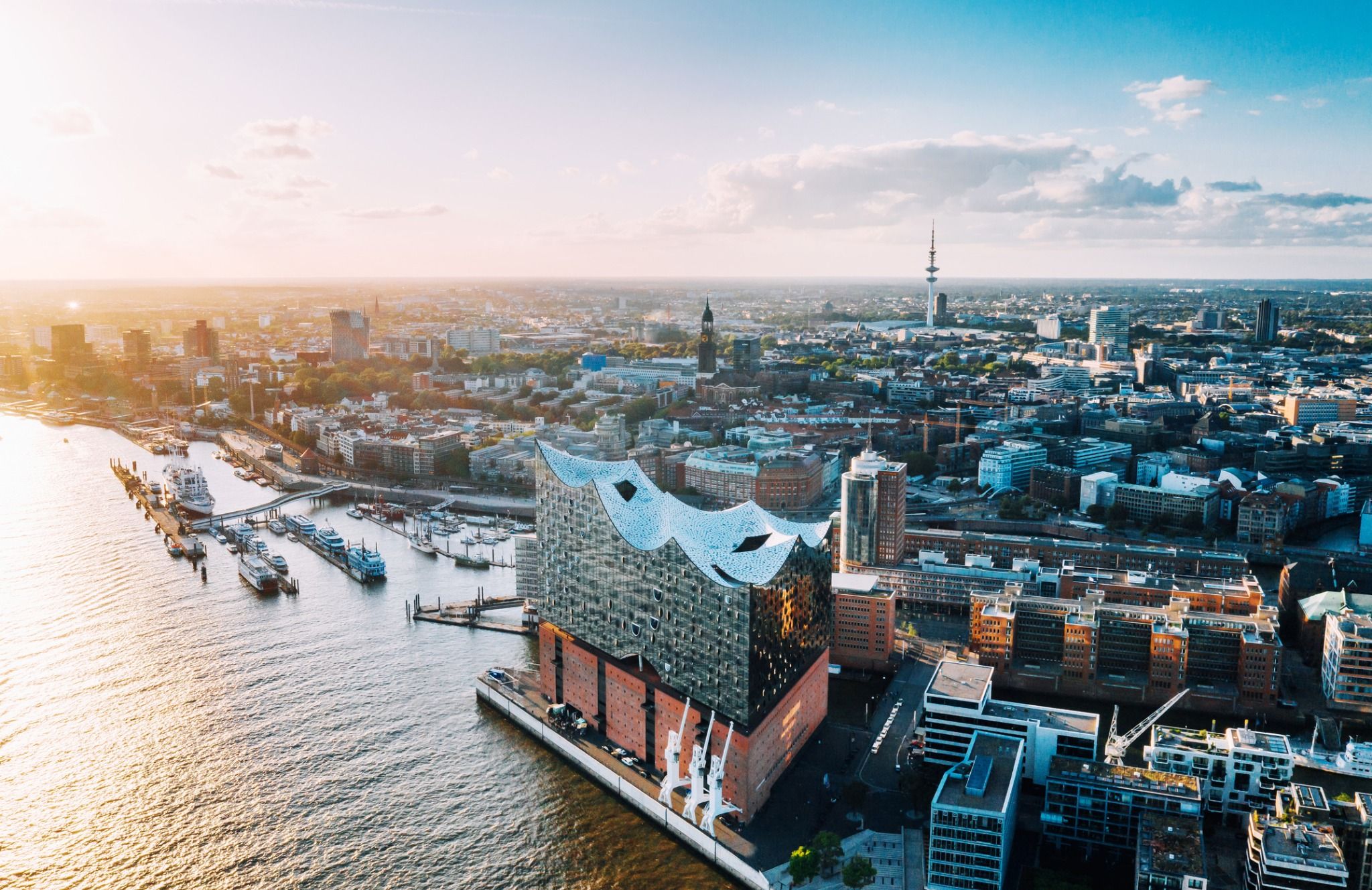 Aerial view of Hamburg, Germany, showcasing the Elbphilharmonie building by the waterfront with the city skyline in the background.