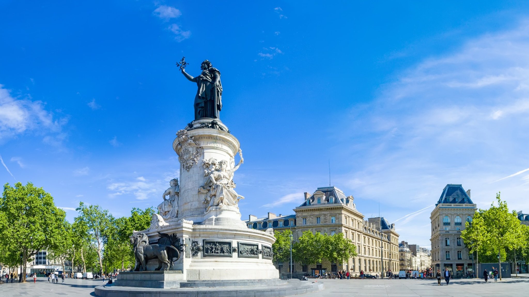 Statue at Place de la République in Paris with surrounding buildings under a blue sky