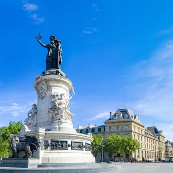 Statue at Place de la République in Paris with surrounding buildings under a blue sky